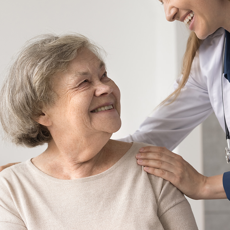 Eine ältere Patientin wird herzlich betreut. Sie lächelt zufrieden.