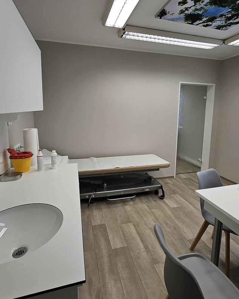 Detail von einem Behandlungszimmer mit sterilem Waschtisch und Liege.