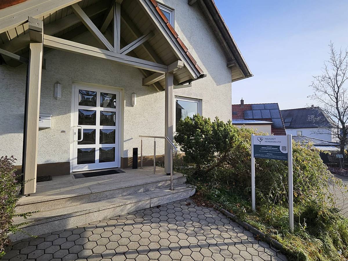 Aussenansicht des Eingangs der Hausarztpraxis mit Firmenschild seitlich